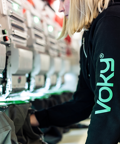 Voky-anställd arbetar med brodyrmaskiner